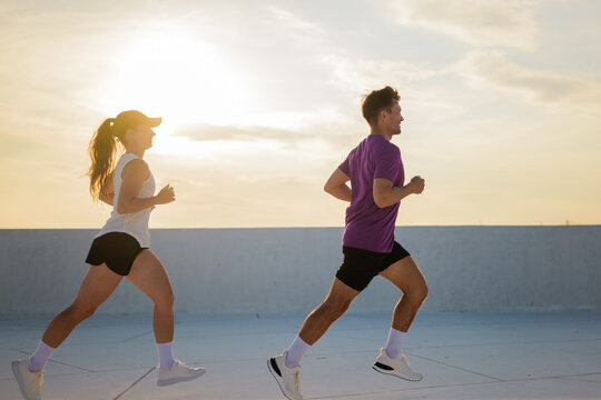 Couple enjoying a vibrant sunset jog along a scenic outdoor track for health and connection