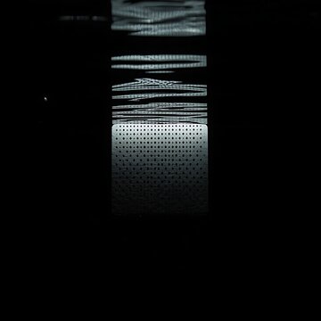 A perforated punch card submerged in still black water, faint refracted light, silent and cryptic mood.