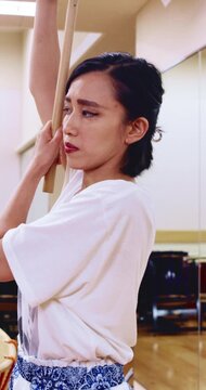 Japanese woman, teacher and studio with drum sticks in class for taiko tradition, culture or practice. Learning, asian musician or female person with skill for music lesson, sound or percussion art