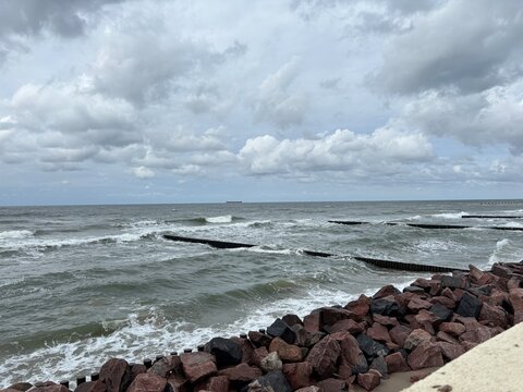 Rocky shoreline with waves crashing under a cloudy sky  