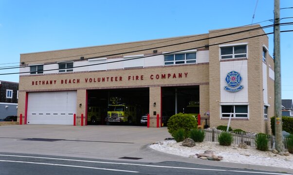 Sussex County, Delaware, U.S.A - Jul 1, 2026 - Bethany Beach Volunteer Fire station with multiple bays, yellow fire trucks, red accents, and landscaped frontage along Route 1