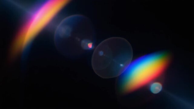 Multicolored lens flares on black background with bokeh effect