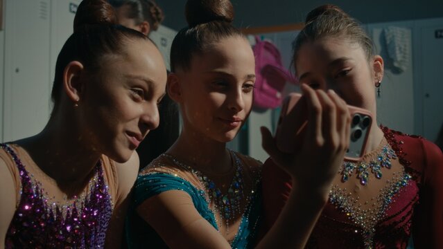 Three Teenage Sitting Together and Looking at Mobile Screen. Girl in Great Mood Exchanging Supportive Looks While Reviewing Performance. Healthy Competitive Spirit, Mutual Support, Camaraderie.