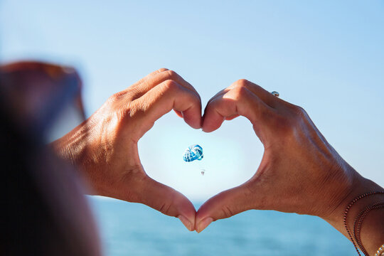 Love gesture framing parasail in sky beach lifestyle