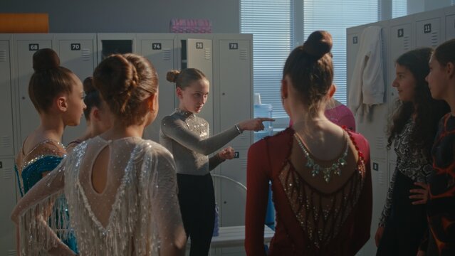 Teenage Female Athletes Standing in Circle, Touching, Examining Each Other Crystal Embroidered Performance Leotards. Girl Pay Compliments Teammates, Creating Supportive Atmosphere Before Competition.