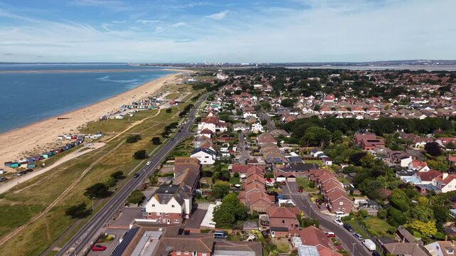 Cinematic aerial drone footage of Hayling Island Beach in Hampshire, England, featuring the expansive coastline, sandy and shingle beach, clear coastal waters