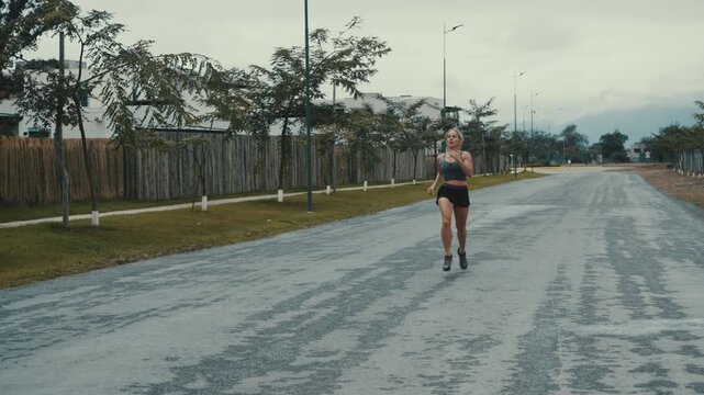 Wide angle of woman running past roadside trees on a cloudy paved street