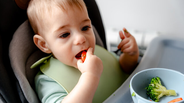 Baby enjoying first solid foods with baby-led weaning