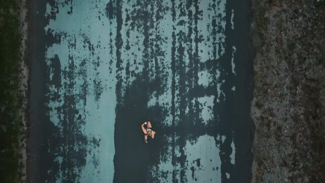 Aerial view of female runner sprinting down textured paved countryside road