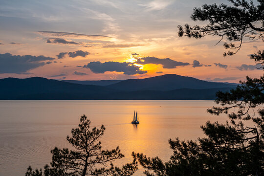 Two yachts on a scenic lake against the backdrop of a picturesque sunrise