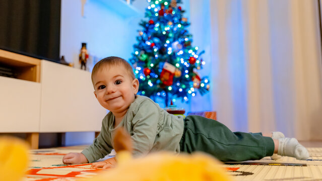 Joyful baby enjoying Christmas by decorated tree