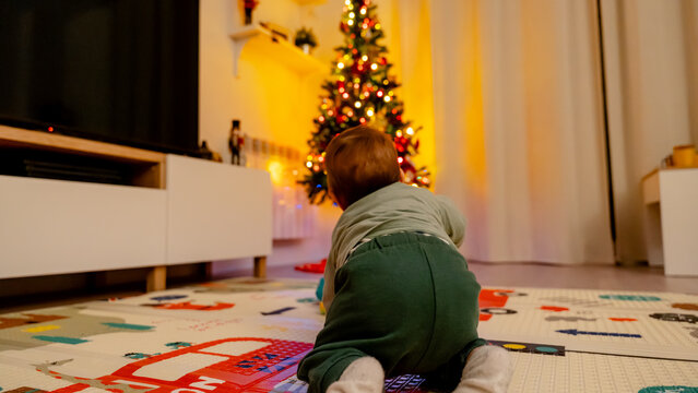 Baby crawling towards a decorated Christmas tree