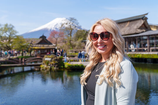 Blonde tourist woman poses at Oshino Hakkai, a scenic traditional village near Mt. Fuji