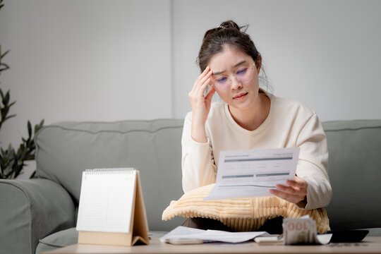 Financial stress concept. Young woman reviewing household bills and expenses at home while planning personal budget and managing monthly finances. Finance, budget, bills, expenses, planning