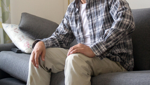 ソファーに座る落ち着かない中年男性