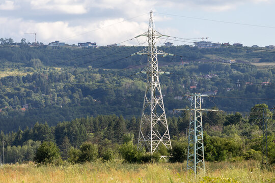 Electricity Transmission Towers in a Landscape with Forest and Suburban Buildings on the Horizon