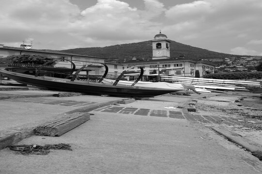 Bateau traditionnel sur la rive du lac de C&ocirc;me devant une &eacute;glise en noir et blanc