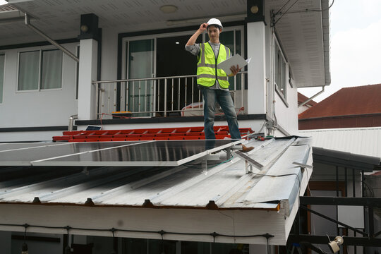 Engineer Inspecting Solar Panel Installation on Residential Home Rooftop with Clipboard