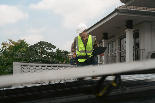 Solar Panel Technician Inspecting Installation on Residential Home Rooftop with Clipboard and Tool Belt