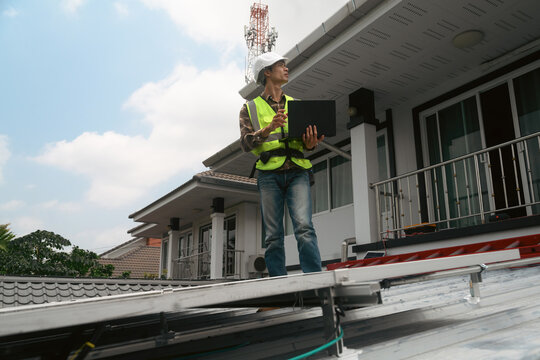 Solar Panel Technician Inspecting Installation on Residential Home Rooftop with Tablet