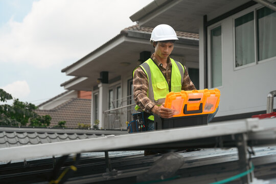 Solar Panel Technician Installing Panels on Residential Rooftop with Toolbox