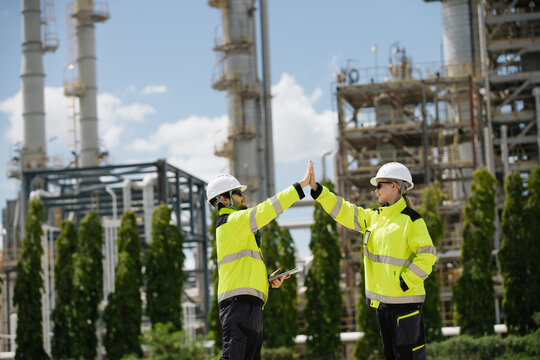 Team of engineers sharing a joyful moment with a high five in front of a contemporary industrial construction site