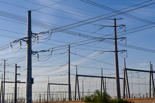 High voltage transmission lines and utility poles near an electrical substation, representing power distribution infrastructure, grid reliability, and energy transmission systems