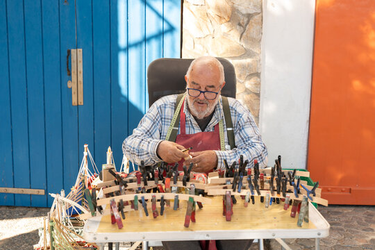 Artisan building wooden model boat at market in Palamos
