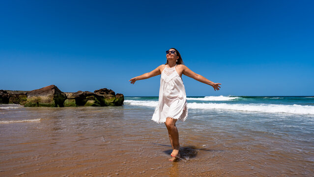Beautiful middle-aged woman enjoying walk on beach on sunny summer day
