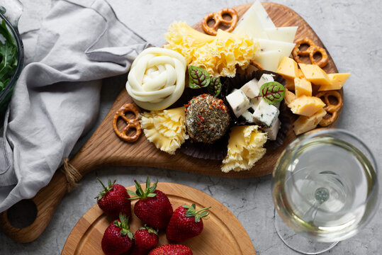 Gourmet cheese board with pretzel and white wine flat lay