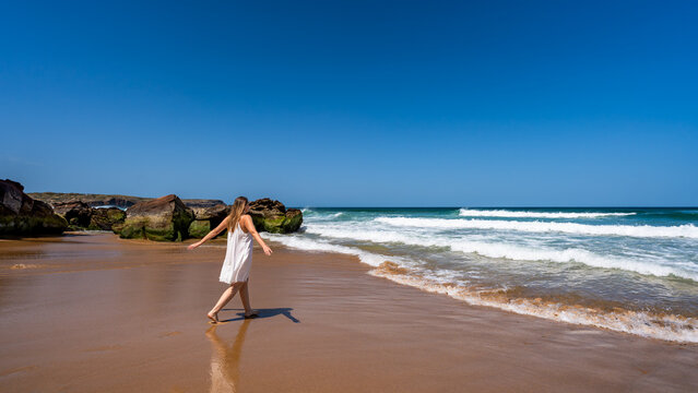 Beautiful middle-aged woman enjoying walk on beach on sunny summer day
