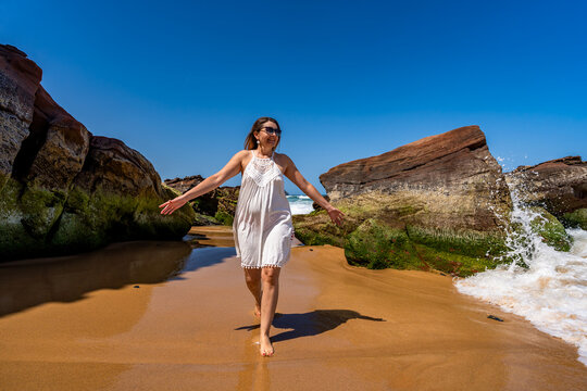 Beautiful middle-aged woman enjoying walk on beach on sunny summer day
