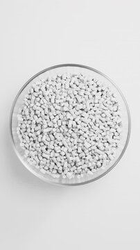 Rotating glass bowl filled with white polypropylene plastic granules and masterbatch resin pellets on white background, 3D render seamless Vertical video.