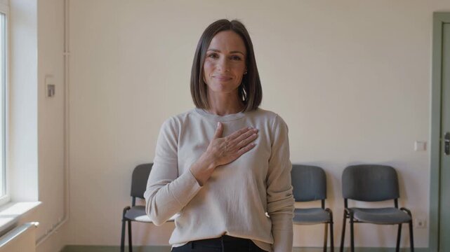 Smiling woman placing hand over heart to show gratitude. Sincere expression of kindness and appreciation. Friendly lifestyle gesture for emotional connection concept.