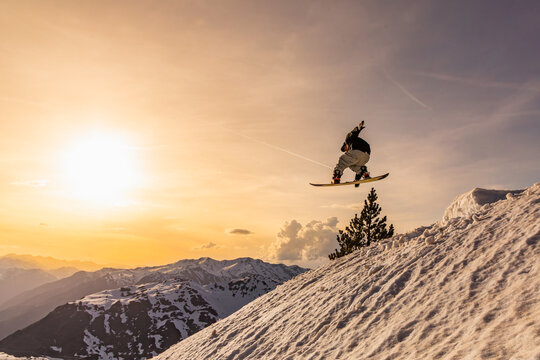 Snowboarder soaring through winter landscape at sunset