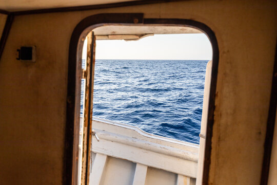 View of open sea through a boat door at sunset