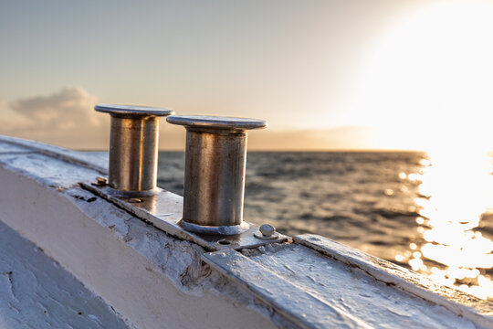 Metal boat bollard on deck with sea at sunset light