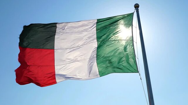 Flag of italy waving in the wind against a clear blue sky