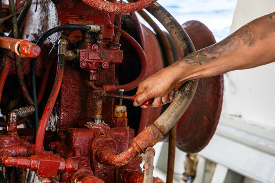 Fisherman repairing rusty boat engine with tools at dock