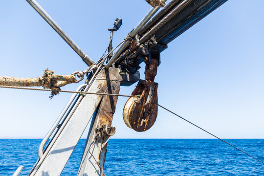 Close-up of rusty ship pulley and rigging above blue sea
