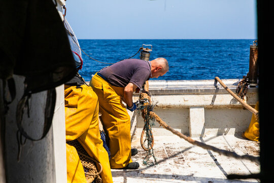 Fisherman hauling rope on fishing boat deck at sea