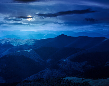 mysterious mountain landscape in summer at night. travel ukraine background. full moon over rolling hill in dappled light. scenic view of borzhava ridge. carpathian mountain scenery