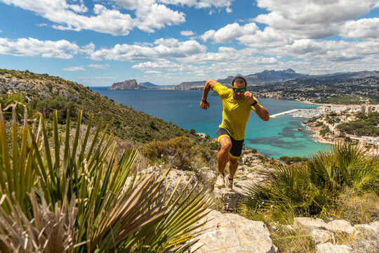 Man trail running by the sea on a sunny day