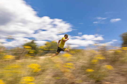 Man trail running swiftly through scenic landscape