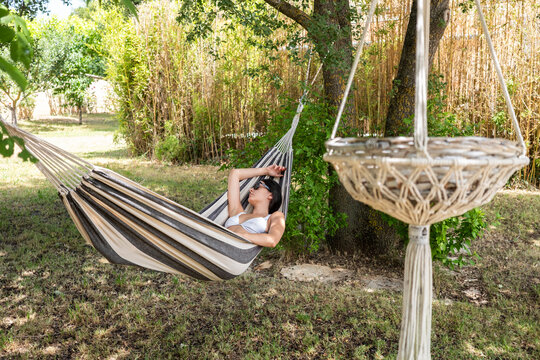 Woman relaxing in a hammock under trees in a garden