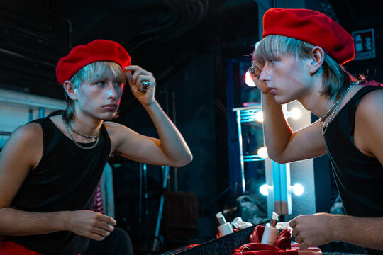 Actor adjusting red beret at backstage dressing mirror