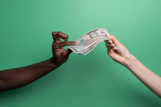 Multiethnic hands exchanging cash over green background