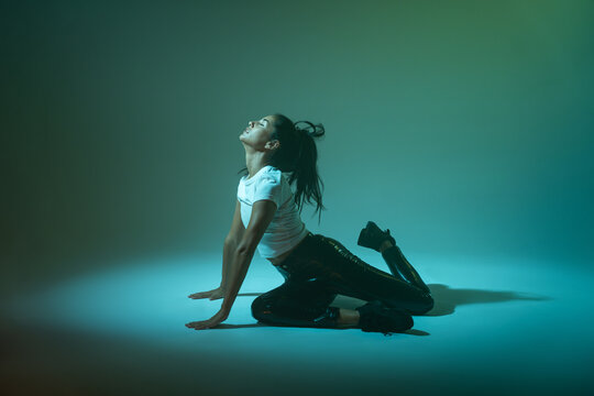 Woman dancer posing on studio floor in teal light