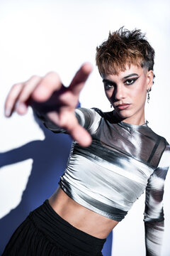 Young woman fashion model reaching toward camera in studio