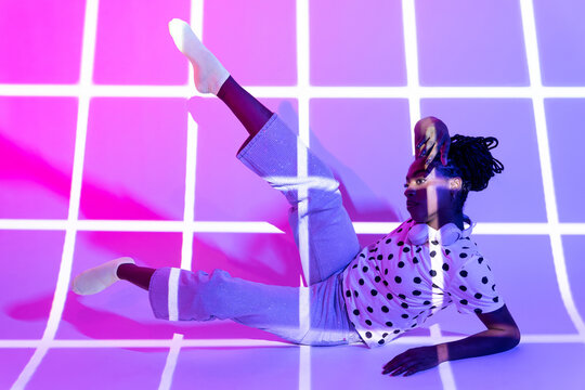 Afro woman dancer in polka dot shirt with neon grid light